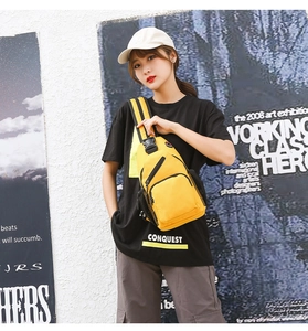 Detail view of yellow oxford canvas chest bag with zippers shown worn by a model