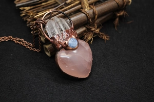Macro detail of heart-shaped rose quartz pendant with copper wire wrap and crystal points