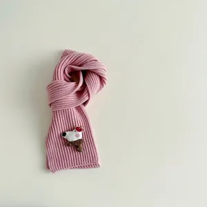 Close-up of pink ribbed knit kids scarf with cute cartoon dog and mushroom patch