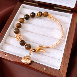 Detail of 18K gold plated tiger eye beaded bracelet with lucky charm in wooden box