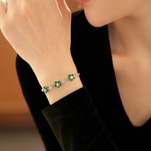 Macro shot of silver chain bracelet with green and white cubic zirconia flower accents