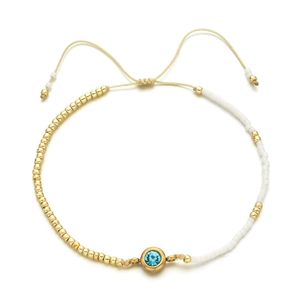 Detail of adjustable gold bead bracelet with sky blue gemstone and white decorative beads
