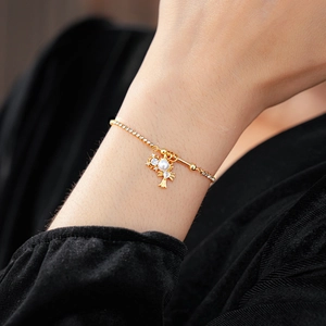 Gros plan d'un bracelet doré avec pendentifs croix, perles et strass sur poignet
