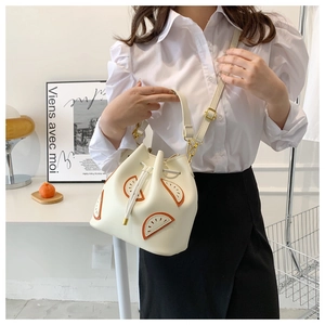 Detail of white PU leather bucket bag with citrus fruit patchwork and drawstring closure