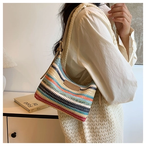 Detail of colorful striped woven straw shoulder bag with adjustable leather strap