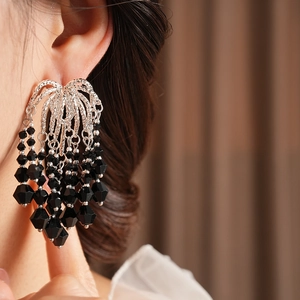 Close-up of elegant black beaded tassel earrings on a model with silver metal details