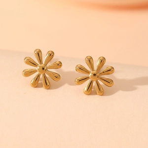 Macro detail of gold flower stud earrings with a glossy eight-petal design and smooth finish