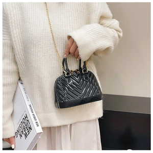 Mini black jelly shell bag with gold chain strap shown on model for size perspective