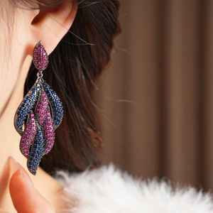 Detail of leaf-shaped drop earrings with navy blue and rose zircon on the model