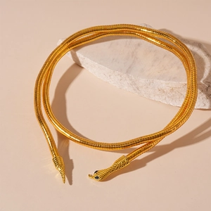Metallic gold flexible snake necklace with textured scales and black gem eyes on white stone