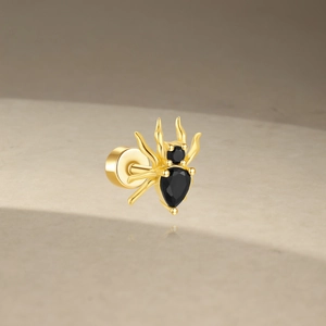 Macro shot of gold spider cartilage stud with black gems and screw flat back design