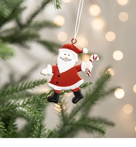 Detail of painted metal Santa Claus ornament hanging on a Christmas tree branch