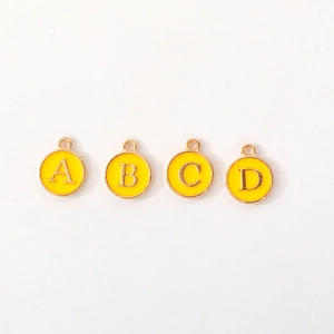 Close-up of yellow enamel and gold-plated alloy circular alphabet charms A B C D