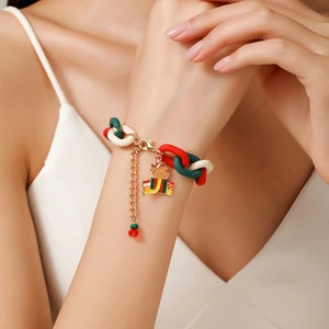 Detail of Christmas bracelet with red and green rings and cute bear charm on model wrist