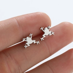 Polished silver frog stud earrings in stainless steel held to show natural size