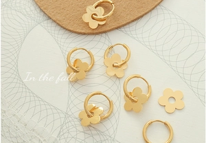 Detailed macro view of 18K gold plated flower earrings on textured paper background