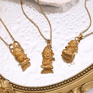 Détail de trois pendentifs Sun Wukong plaqués or 18 carats sur un miroir avec de l'eau