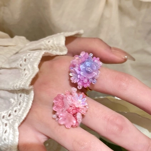 Close-up of resin flower rings with pink and purple petals on a gold metal band