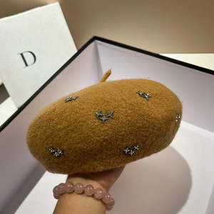 Close-up of star rhinestones on a warm camel wool beret with minimalist packaging