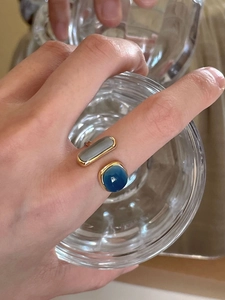 Detail view of gold open ring featuring square grey and round blue cabochon stones
