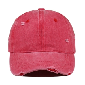 Macro detail of distressed washed red cotton baseball cap showing frayed edges and holes