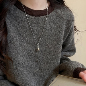Silver Y-shaped long sweater necklace with star pendant on grey knit sweater close-up
