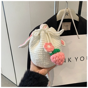 Detail of handmade crochet bucket bag with rabbit ears and strawberry charm