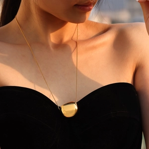Minimalist 18k gold plated stainless steel pebble pendant necklace worn by a female model