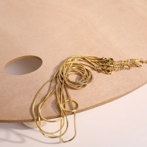 Polished 1.5mm gold snake chains set with adjustable lobster clasps on wooden palette