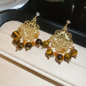 Close-up of gold filigree earrings featuring tiger eye beads and square zircon stones