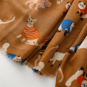 Close-up detail of cartoon cat patterns and tassel fringe on a brown cotton linen scarf