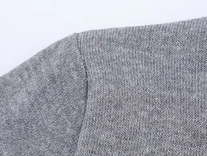 Detailopname van de grijze gebreide textuur en schoudernaden van dit gebreide T-shirt