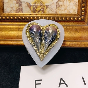 Macro view of heart-shaped silicone mold featuring realistic bird skulls and baroque patterns