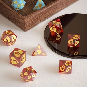 Gros plan d'un jeu de dés polyédriques en résine rouge avec des gravures de cœurs dorés