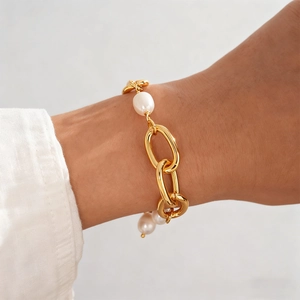 Detail of 18k gold-plated chain bracelet with faux pearls worn on a woman's wrist