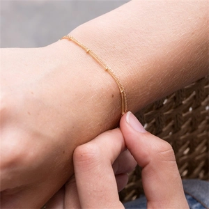 Close-up of a minimalist gold-plated satellite chain bracelet worn on a female wrist