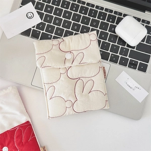 Detailed close-up of quilted cotton storage pouch with rabbit embroidery on laptop