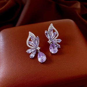 Detail of purple zircon butterfly drop earrings on luxury textured leather background