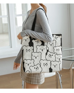 Detail of large capacity canvas tote bag with cartoon bear print worn by a model