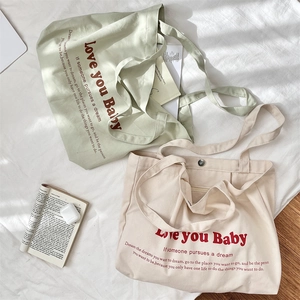 Detail of canvas tote bag with metal snap closure and 'Love you Baby' printed text