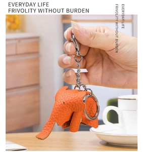 Detailed macro of a cute orange genuine leather elephant keychain held in hand