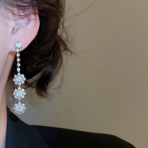 Detail view of elegant silver floral drop earrings with sparkling clear crystals on model
