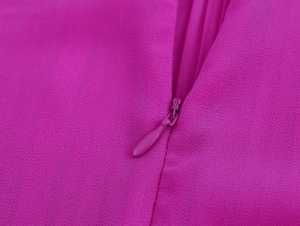 Dettaglio della cerniera invisibile e del tessuto chiffon sull'abito rosa scuro