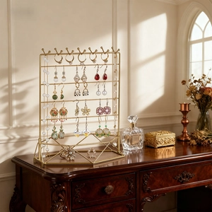 Elegant gold iron jewelry display stand for necklaces and earrings on a vintage dresser