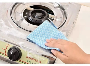 Blue wave pattern cleaning cloth wiping heavy grease off a stainless steel stove