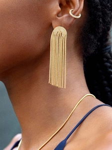 Close-up of golden tassel earrings with zircon ear cuff and multi-layer chain details