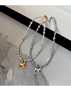 Close-up of gold and silver rocking horse pendants on pearl and bead necklace strands