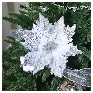 Close-up of a white and silver glitter poinsettia flower on a green Christmas tree