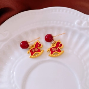 Close-up of red enamel rocking horse earrings with Chinese Pingan blessing on white porcelain