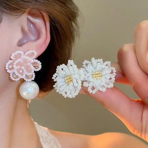 Macro detail of elegant beaded flower earrings with a large white pearl drop